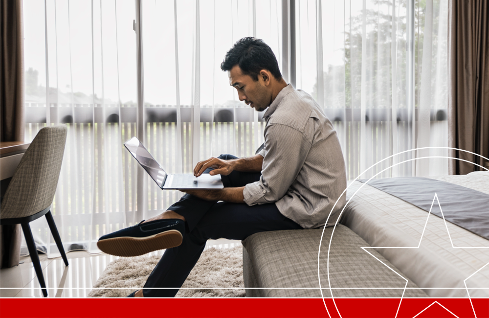 Young Asian businessman working from home, using digital tablet while sitting on bed inside modern house