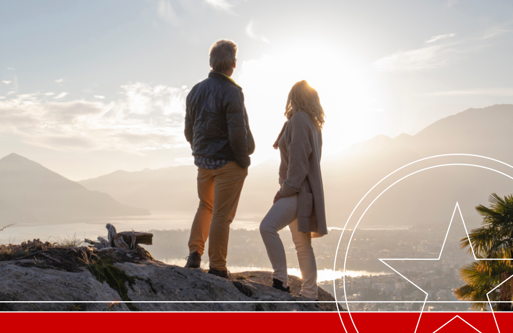 Mature couple hike along sunny mountain ridge, sunset