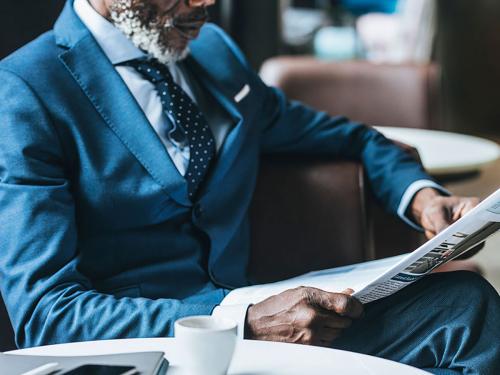 Man in blue suit reading paper