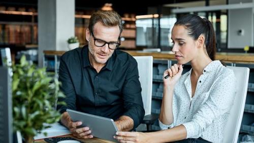 Mortgage Finance Man and Woman in office looking at tablet