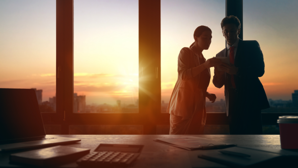 business colleagues meeting in an office while the sun is setting outside the office window