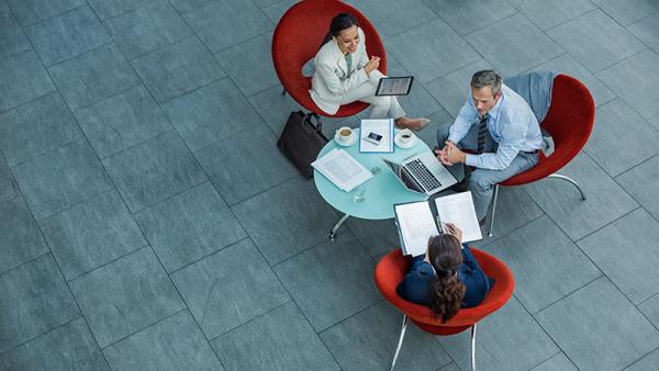 Three people working while sitting in red chairs