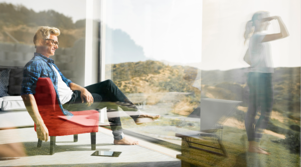 Casual man sitting in modern home with woman standing in garden